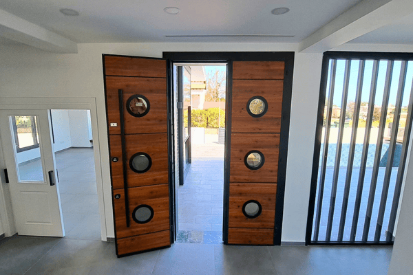 Main entrance with a bold wooden door and nautical-style circular glass inlays.