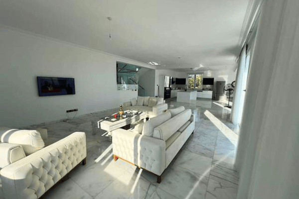 Living room with plush cream furniture, TV unit, and large windows.