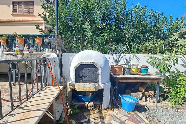 A wide-angle view of an inviting outdoor dining space with comfortable seating and a lush garden backdrop.