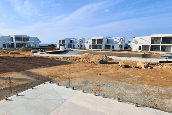 Panoramic aerial shot of development in progress, showing harmonious layout of luxury villas surrounded by lush greenery.
