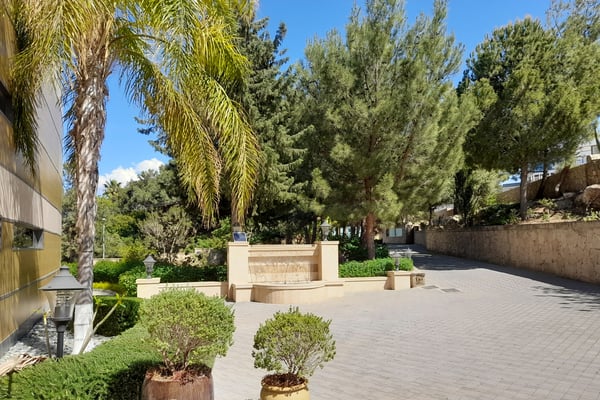 Grand Walkway to Home Entrance with Columns – A beautiful front entrance framed by a grand walkway, classic columns, a possible wrought-iron gate, and manicured lawns with lush green shrubs.