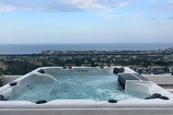 Rooftop jacuzzi with panoramic cityscape views during dusk at an exclusive hillside retreat.