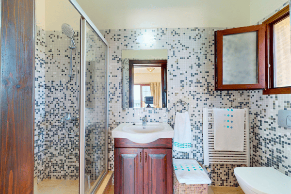 Elegantly tiled bathroom with natural wood and a vanity mirror, evoking a boutique hotel style.