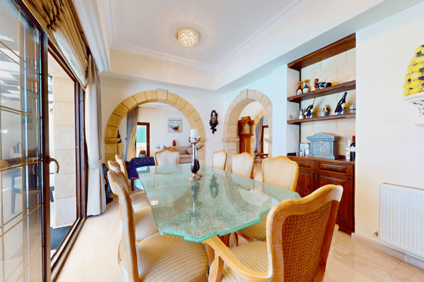 Dining room adjacent to kitchen, highlighted by curved arch openings and Mediterranean-tiled flooring.