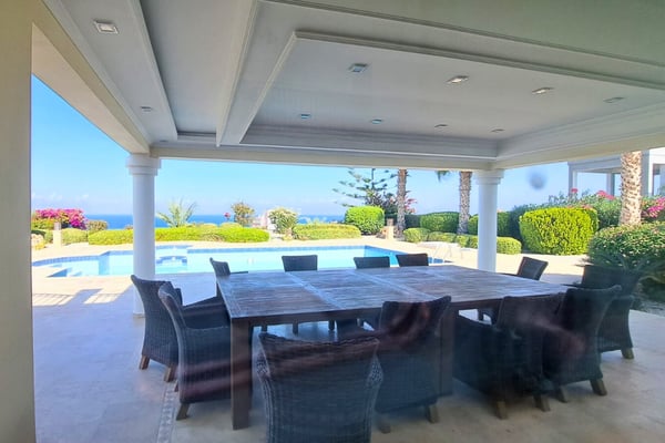 Outdoor lounge area with rattan furniture and ceiling fans, seamlessly extending interior comfort into the covered terrace space.