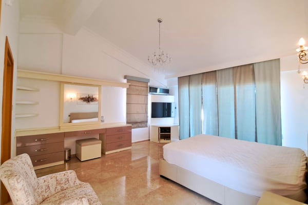 Fifth bedroom with chandelier and sliding wardrobe, combining elegance and versatility in a serene atmosphere.