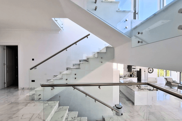 Sleek modern staircase with glass balustrades and marble treads.