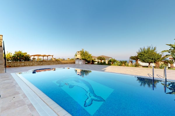 Outdoor lounge area overlooking the swimming pool, complete with comfortable seating and a shaded pergola for relaxation.