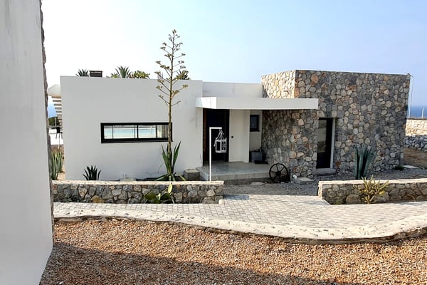 Secluded Stone and White Concrete Villa - A unique villa combining modern white concrete walls with rustic stone accents, situated in a peaceful natural setting with ocean views.