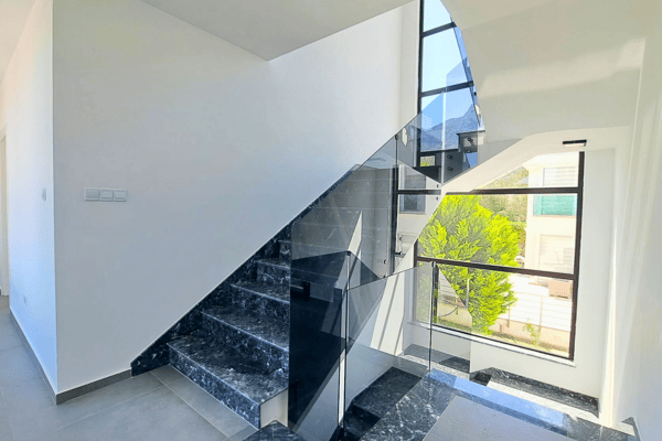 Striking spiral staircase with polished marble steps and sleek steel handrails.