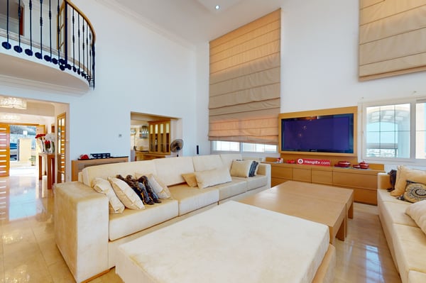Spacious open-plan kitchen with sleek wooden cabinets, high-end stainless steel appliances, and a breakfast bar with stylish bar stools.