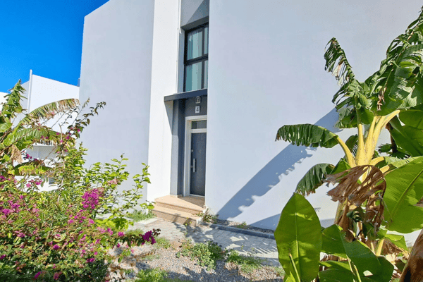 Walkway lined with lush banana leaves and clean white walls, enhancing the villa’s fresh and breezy aesthetic.
