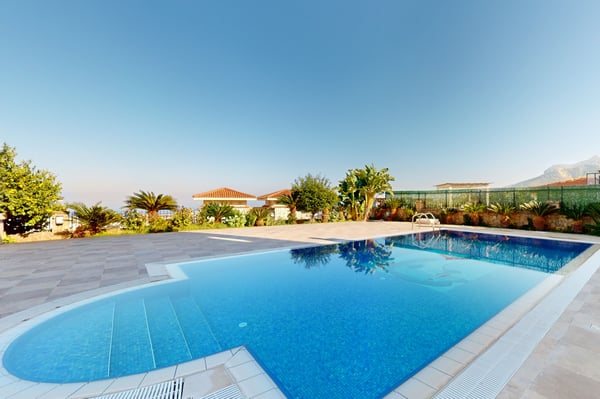 Luxurious infinity swimming pool with crystal-clear water, surrounded by sun loungers and palm trees, providing a relaxing outdoor experience.
