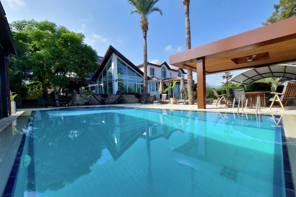 A stunning luxury villa featuring landscaped gardens, two pools, a fitness studio, and a cinema room. Ideal for exclusive living with high-end amenities.