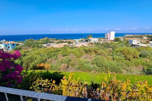 Elevated view across greenbelt to sea bay, emphasizing villa’s privacy and scenic dominance over neighboring rooftops.