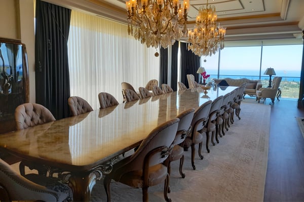 Luxury Living Room with Entertainment Space and Large Windows – A spacious living or entertainment area featuring plush seating, a coffee table, floor-to-ceiling windows or doors, and a tray ceiling with recessed lighting.