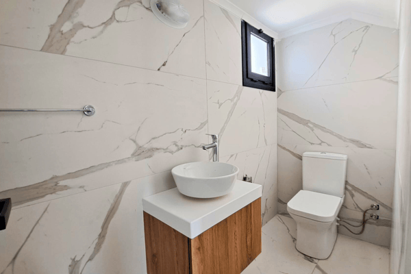Main bathroom with marble-effect tiles, floating vanity, and shower unit.
