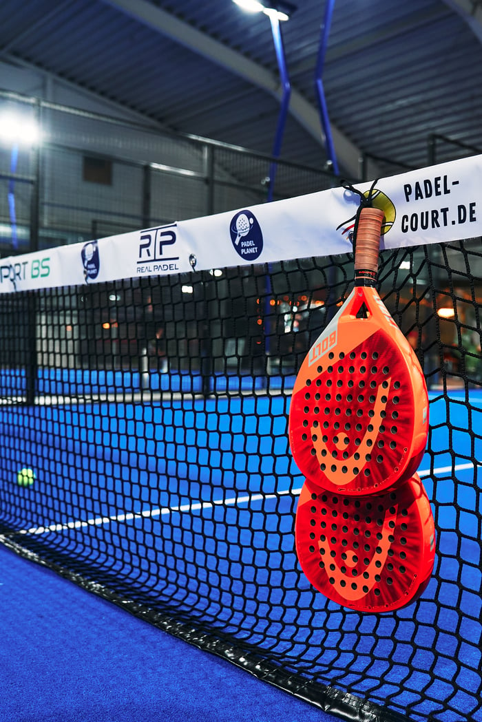 Padel-Schläger die an einem Netz in einer Indoor-halle hängen