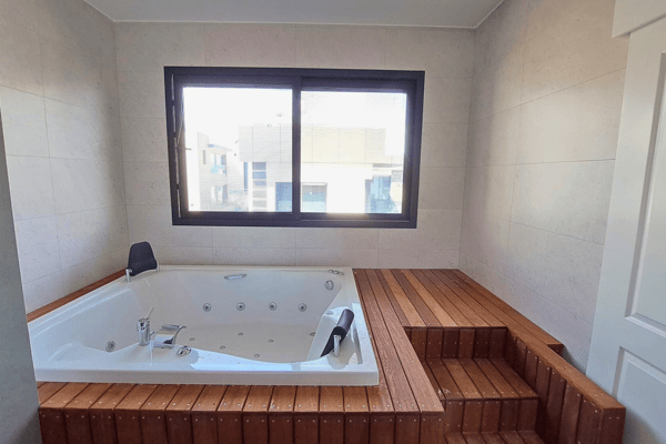 Ensuite bathroom with a rain shower, glass enclosure, and slatted wood feature wall.