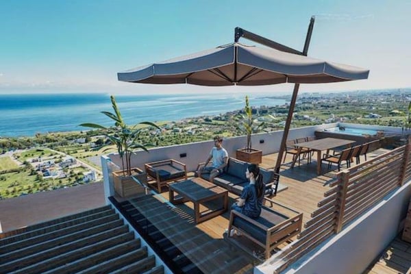Lower angle shows sleek facade and rooftop spa perched above manicured gardens and palm trees, exuding resort-style luxury.