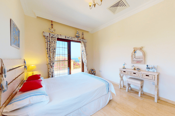 Single bedroom styled with feminine accents, a writing desk, and whitewashed furnishings.