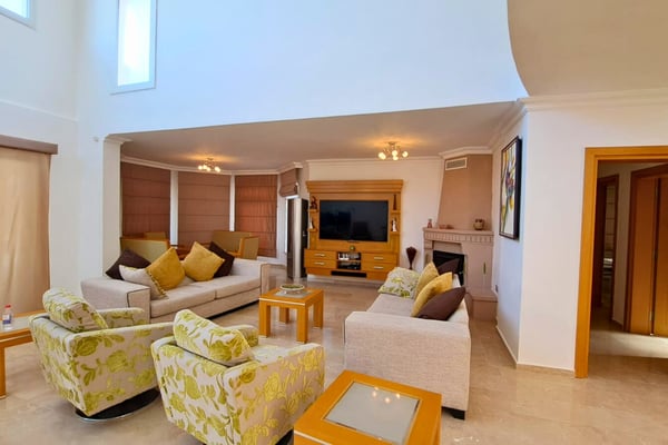 Living room with plush sofas and media wall, bathed in daylight and designed for both comfort and elegant socializing.