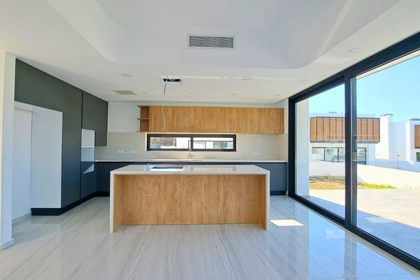 Kitchen view showcasing stylish finishes, modern layout, and integration of natural light through large window openings.