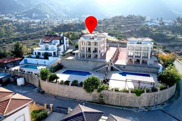 Aerial view of the entire property, showcasing a large private estate with a well-landscaped garden, an outdoor pool, and surrounding green hills.