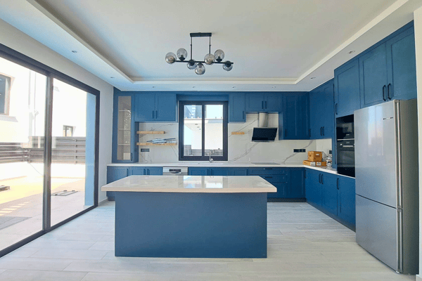 Kitchen angle showing island, pendant lights, blue cabinetry, and natural light.