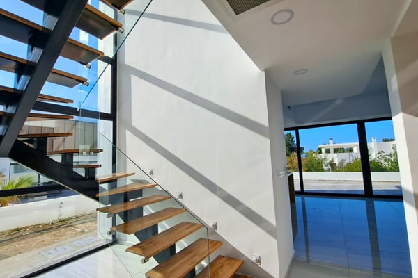 Floating stairs with glass railing and ample daylight, adding transparency and elegance to the interior’s vertical flow.