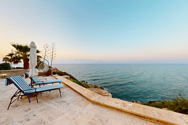 Seafront stone patio with recliners and uninterrupted ocean views—a picture-perfect sunrise or sunset spot.