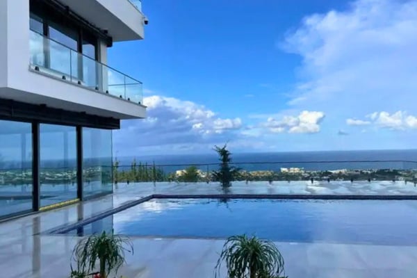 Infinity pool with stunning ocean views at a luxury villa, capturing serene skies and coastal horizon.