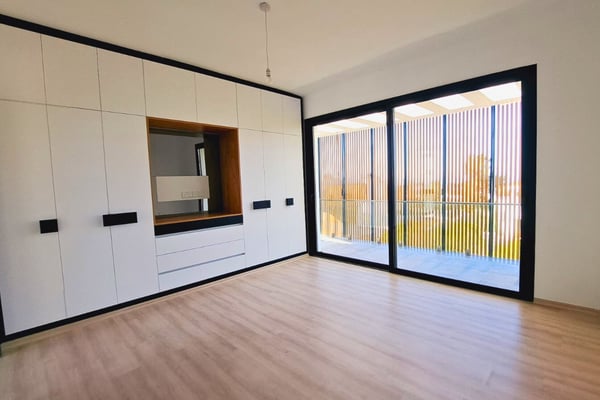 Second guest room with neutral color palette and expansive glazing, maintaining the home’s modern continuity.