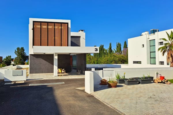 Entrance driveway leading to a modern home with symmetrical lines, gravel landscaping, and low boundary walls enhancing curb appeal.
