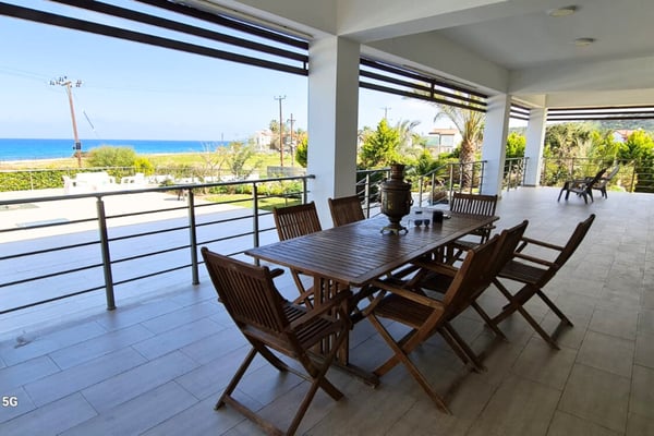 Modern interior of a sea-front villa in Esentepe, Northern Cyprus, showcasing a spacious lounge, designer furniture, and full-length windows.
