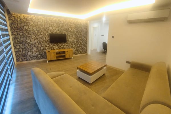 Sunlit lounge with a cozy sofa and natural textures, blending comfort and modern charm in a welcoming living space.