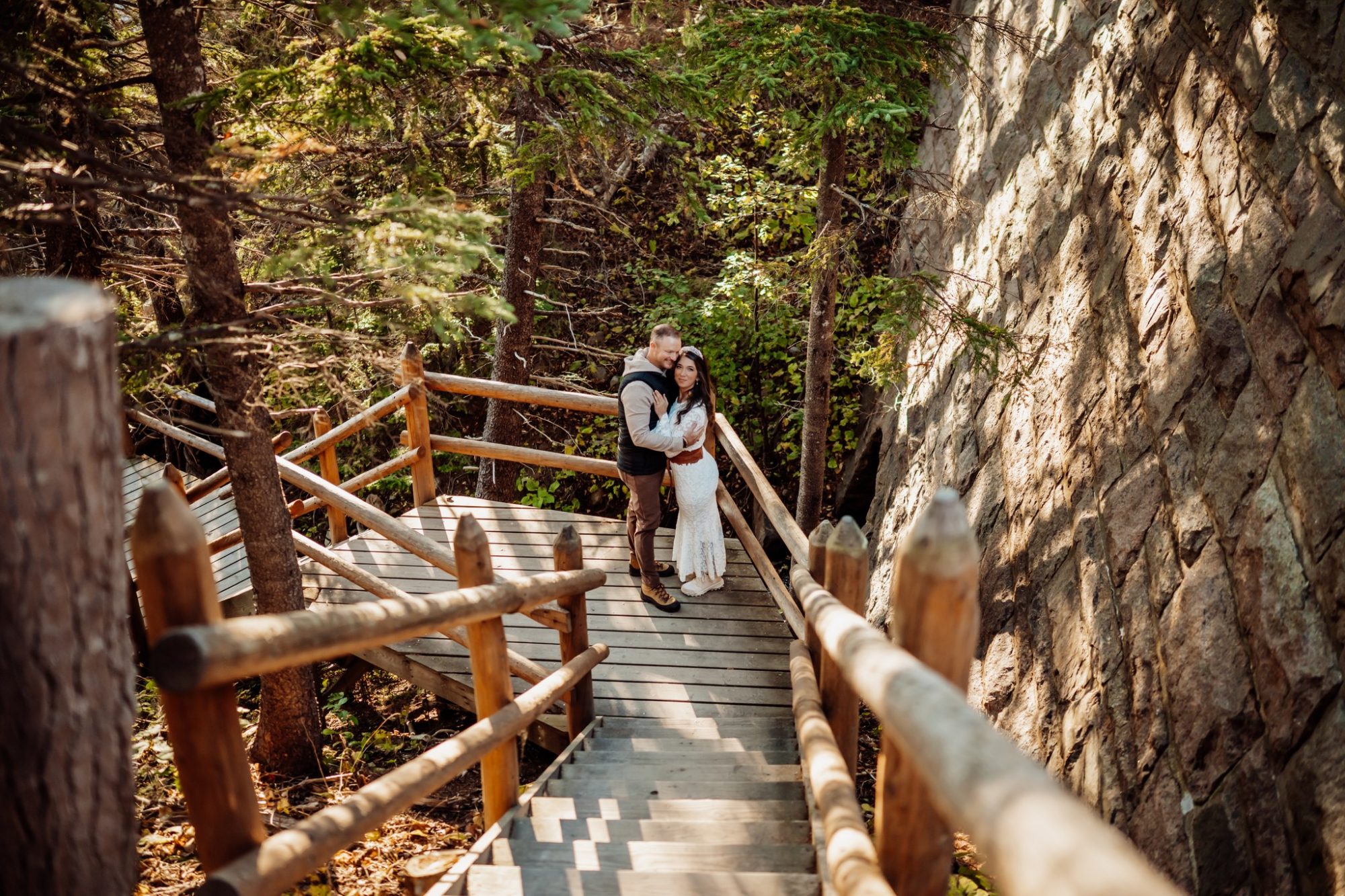 Couple standing on wooden bridge surrounded by fall color in Acadia National Park.
