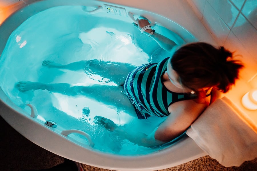 Pregnant woman sitting in a bathtub with blue lights