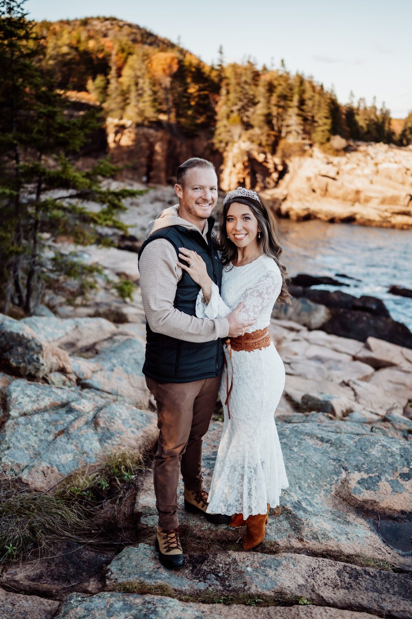 Newly married couple embracing on granite cliffs during fall elopement in Acadia.