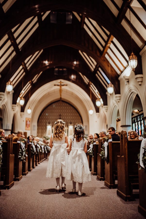 Flower girls walking down isle in church wedding