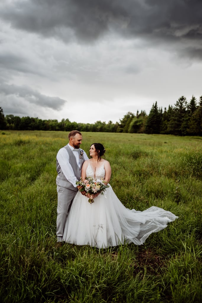 bride and groom standing together in field at sunset meadows