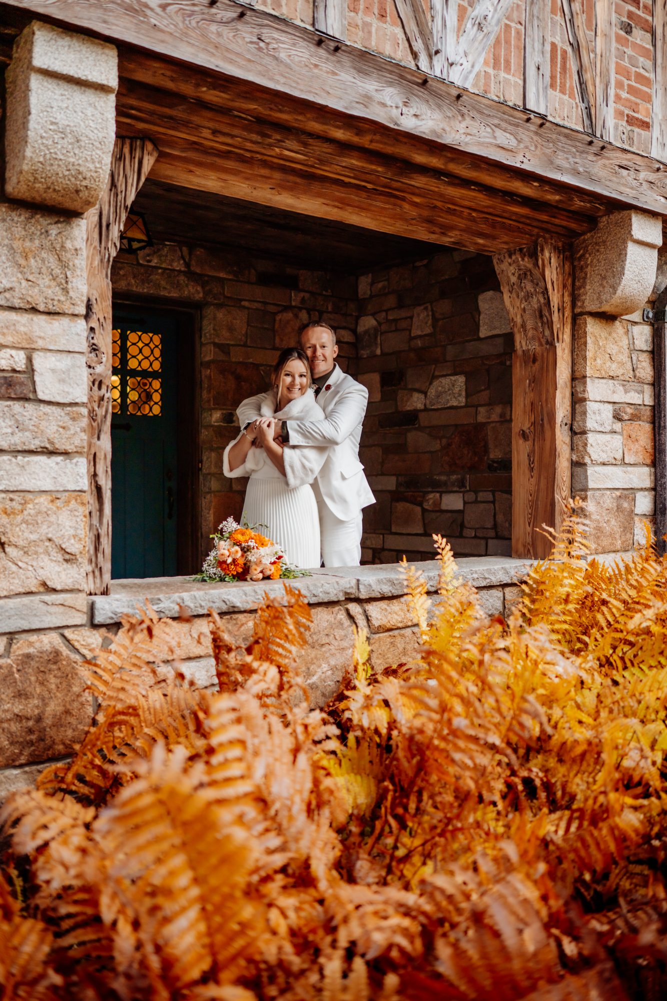 Couple standing in rustic stone building in Acadia during fall elopement.