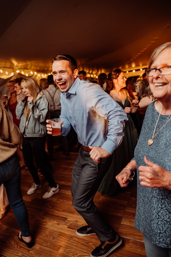 Man with blue shirt holding drink and dancing in crowd