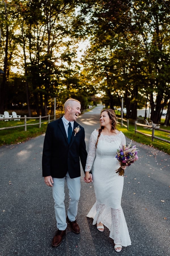 Bride and groom looking at each other laughing and walking in front of Bar Harbor inn