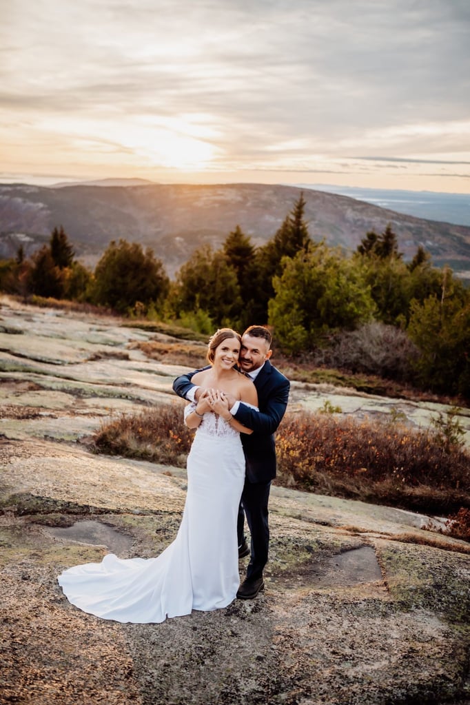 Golden hour elopement portrait at Schooner Head Overlook in Acadia National Park with mountains glowing in sunset light.