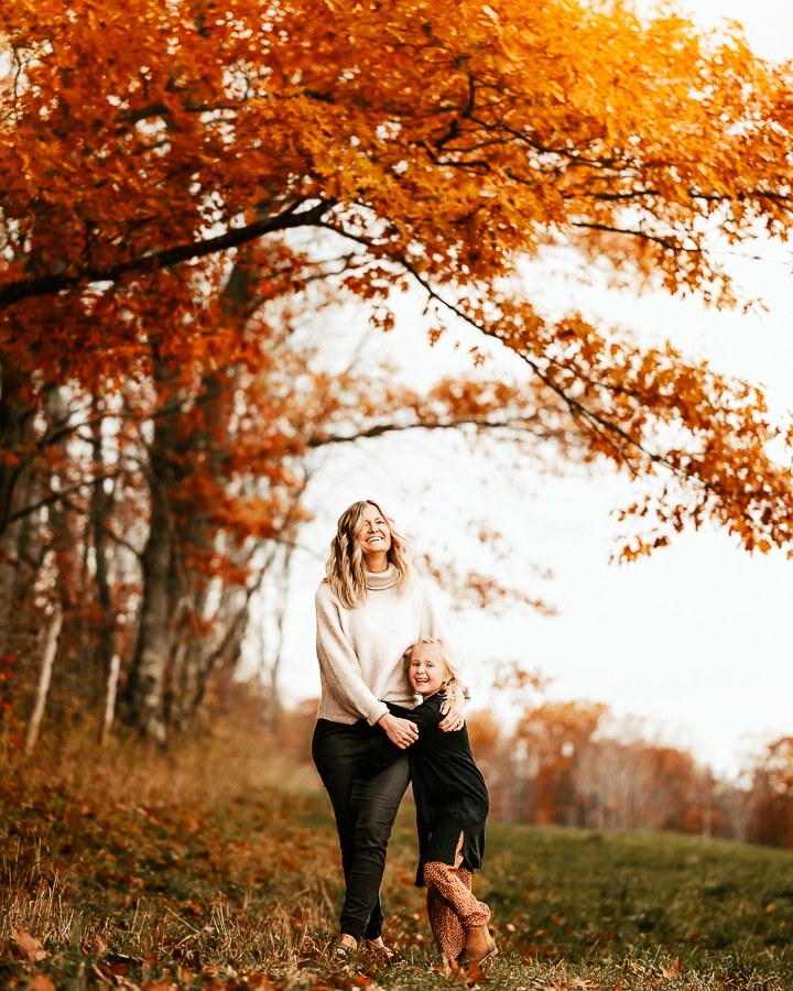 Mother and daughter laughing under orange tree