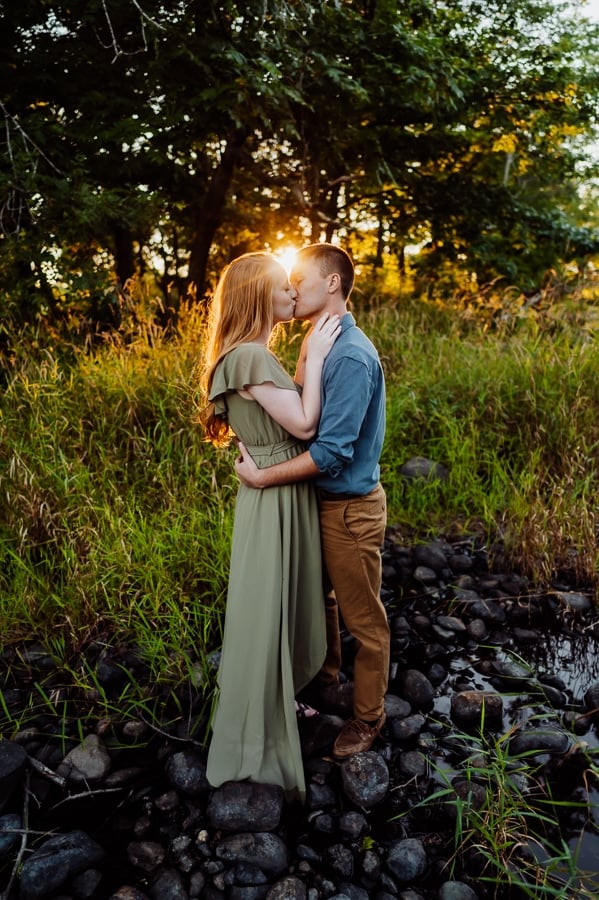 Reached couple standing together kissing with the sunshine between their heads