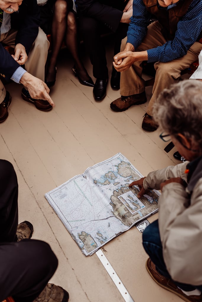 Group of people sitting around a map of MDI on a boat