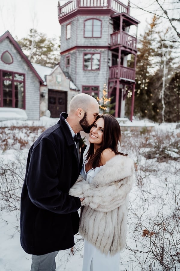 Bride and groom kissing in front of castle like house on MDI