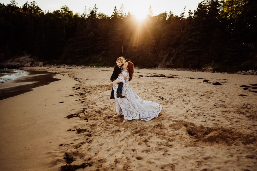 pregnant mother in lace dress on beach holding son